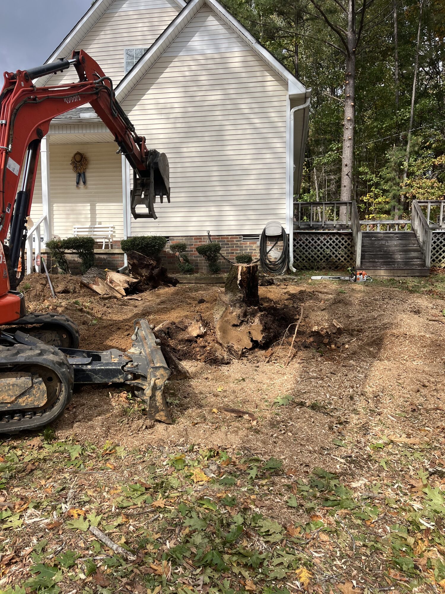 Stump Removal — Stump extraction tight to the foundation Stump removal excavation tight to a home foundation in Selmer TN